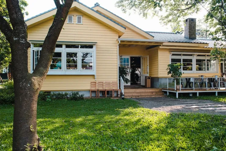 charming-yellow-house-with-wooden-windows-green-grassy-garden_181624-8074